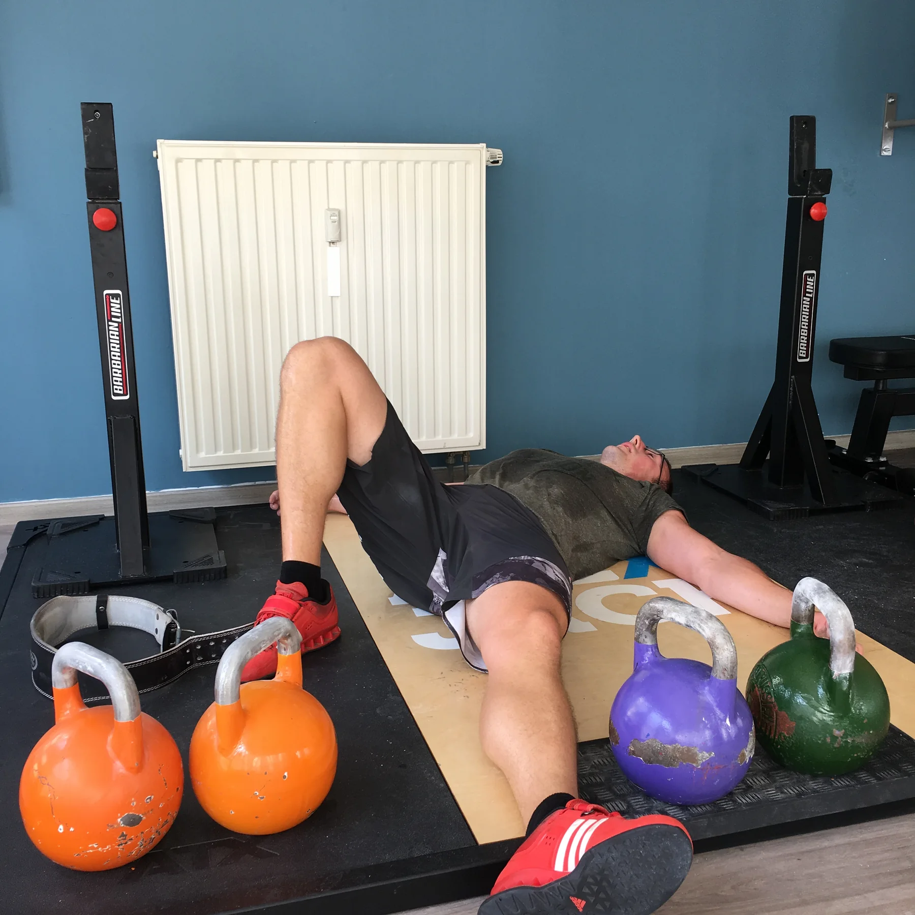 Alexander Jäck liegt nach einer anstrengenden Kettlebell-Einheit zwischen mehreren Kettlebells auf dem Boden