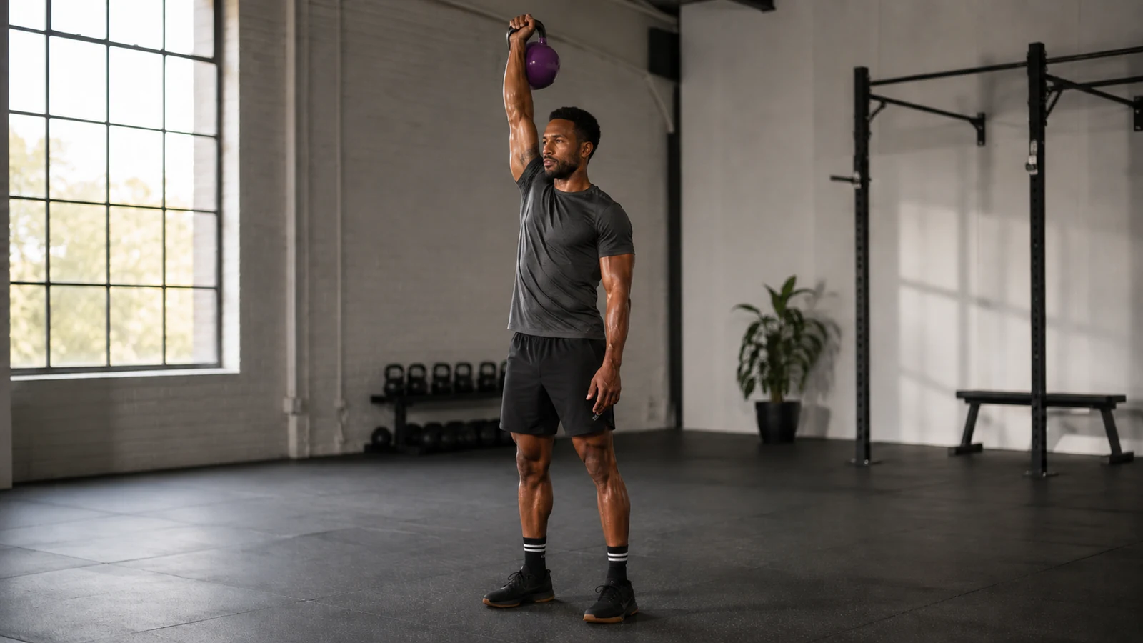 Athlet hält eine violette Wettkampf-Kettlebell stabil in einarmiger Overhead-Lockout-Position.